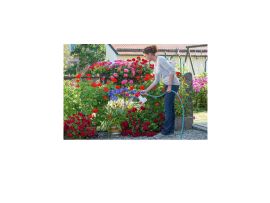 Glückliche Frau beim Gießen und Düngen von Blumen mit dem Aquamix Dossiergerät. Die Pflege der Pflanzen erscheint kinderleicht